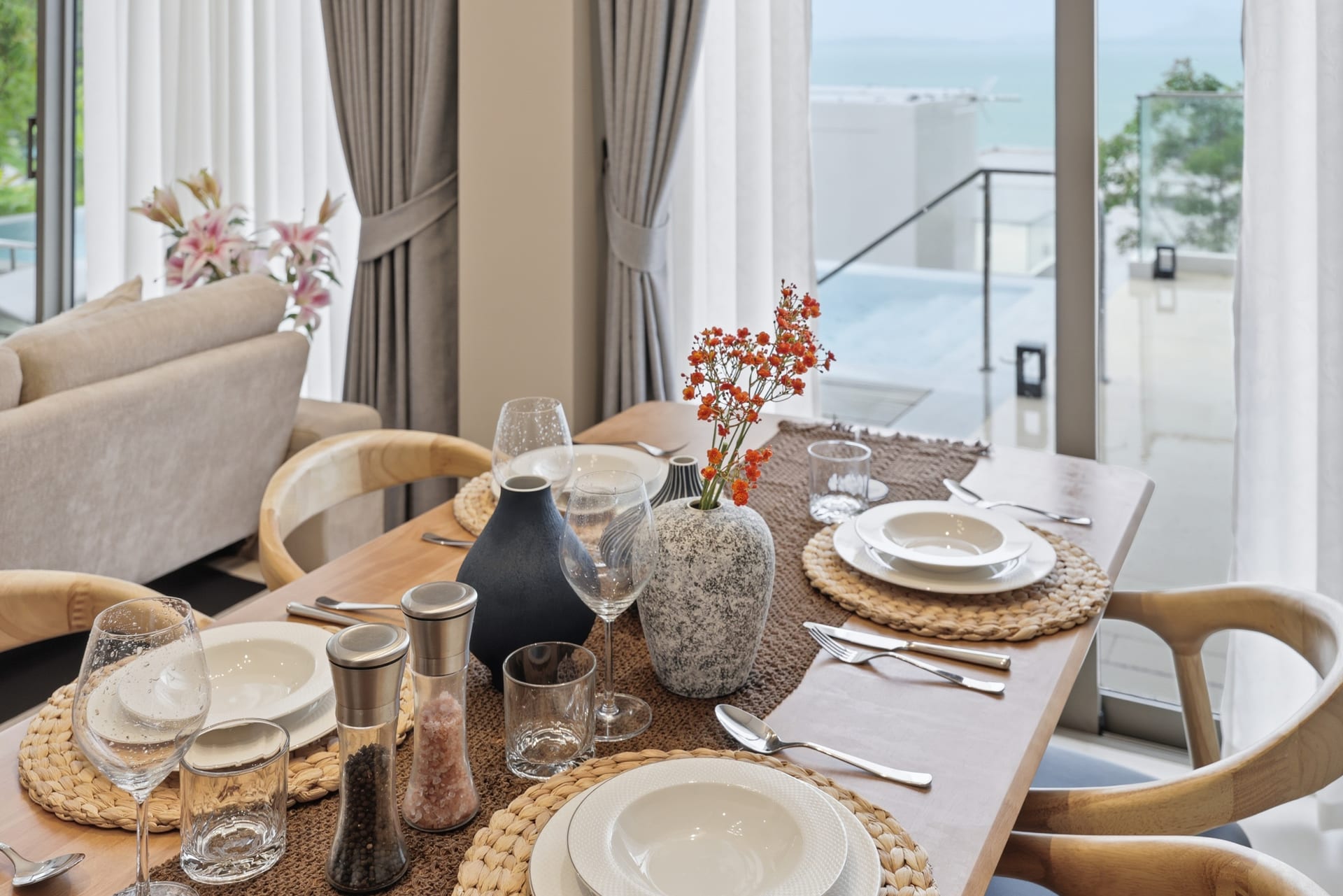 The dining table dressed with orchids and place settings, the sea view through the full-height windows