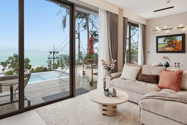 Dining table set for four with the Andaman Sea behind through floor-to-ceiling doors