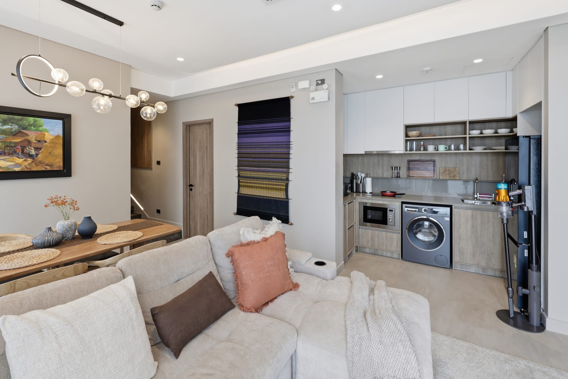 The great room flowing into the open-plan kitchen, sofa in the foreground and the laundry-equipped galley behind