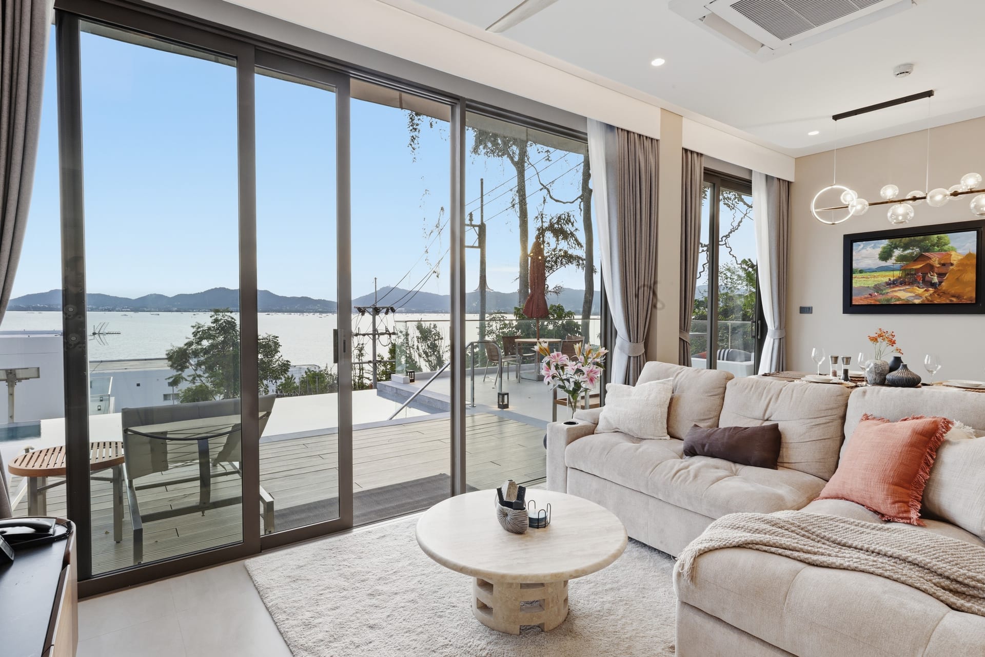 The great room with its sliding doors fully open to the terrace, the pool and the bay just beyond the threshold