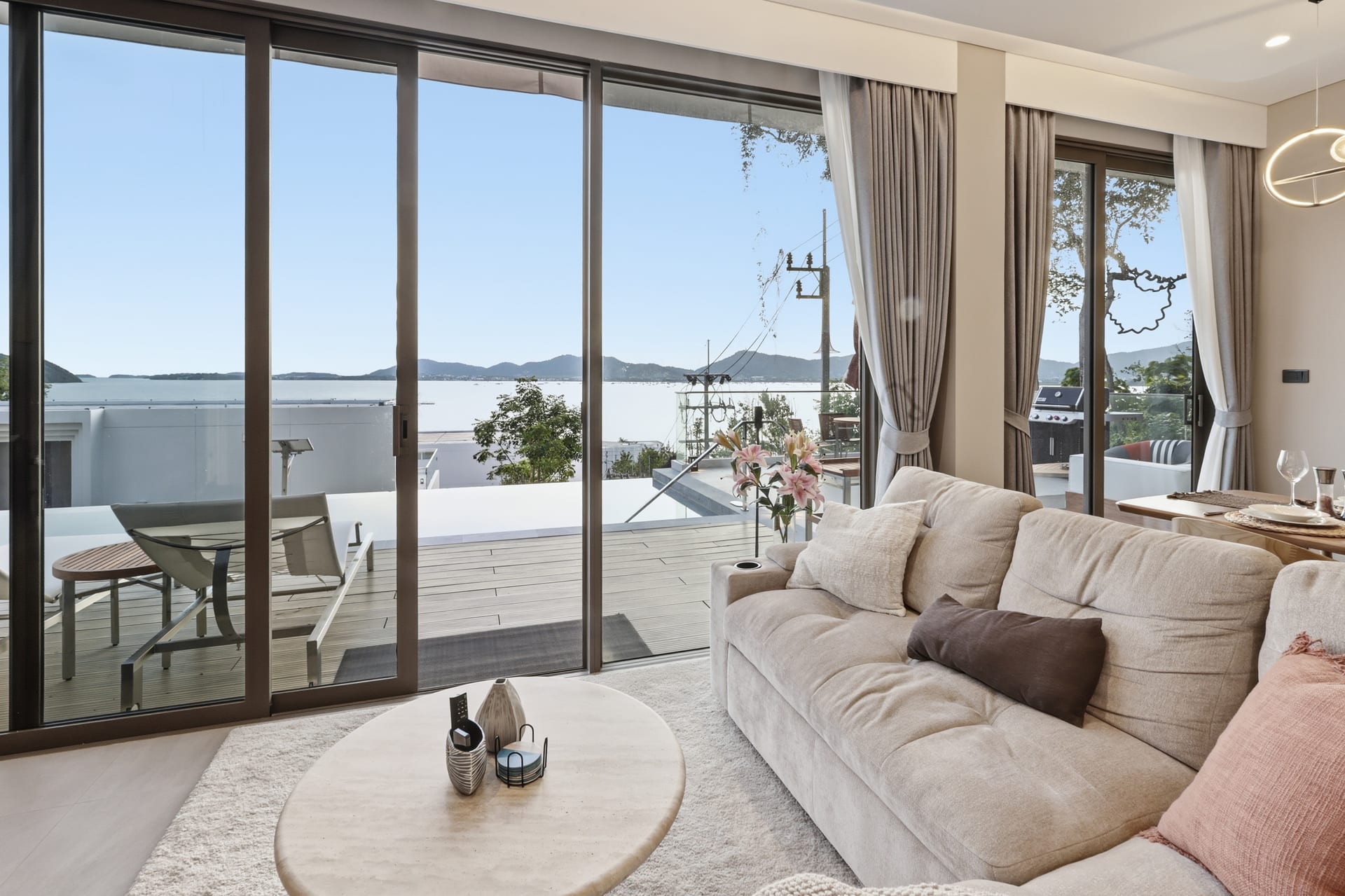 The great room sofa and OLED TV with open sliding doors framing the bay view