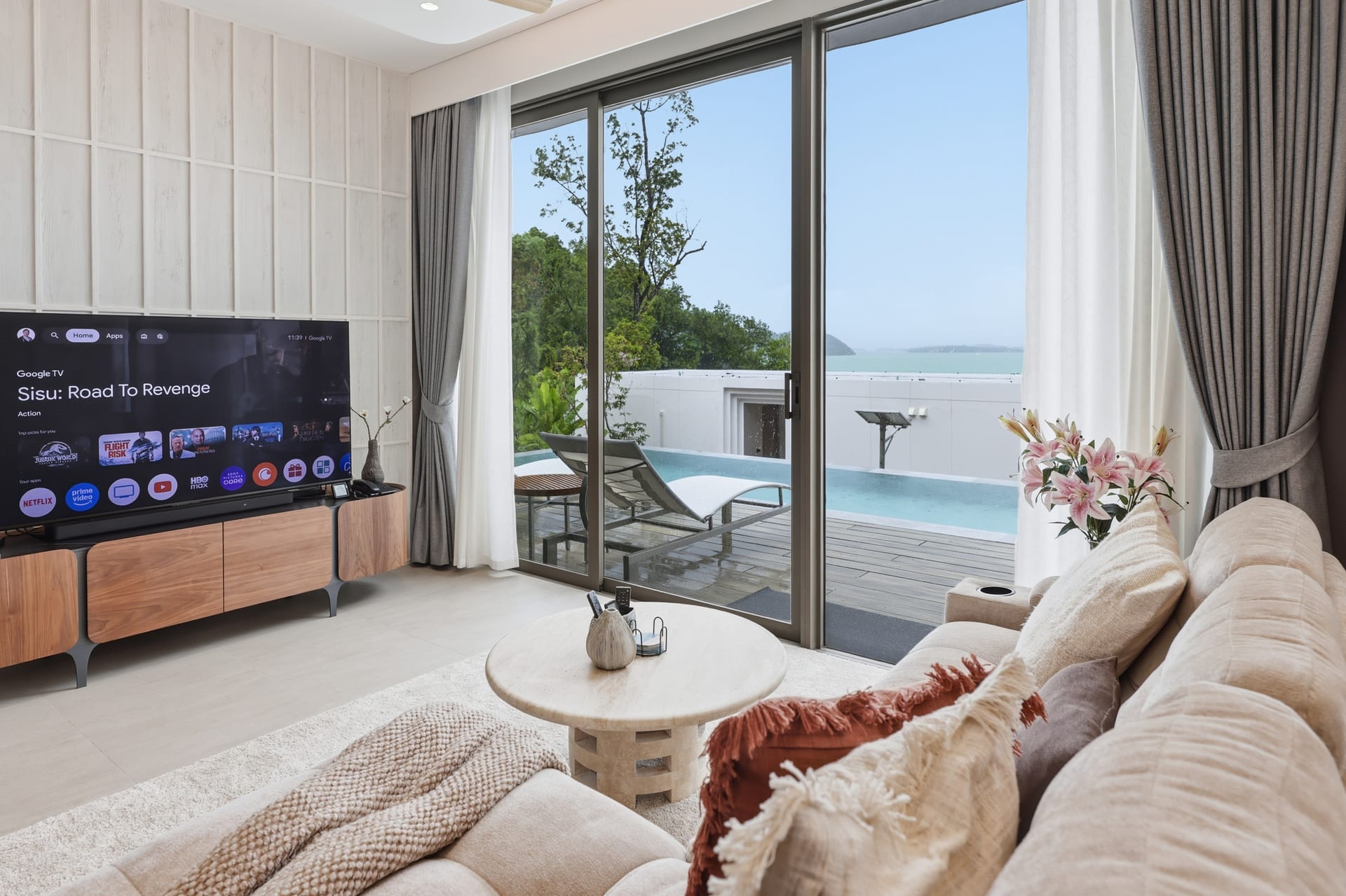 The great room sofa facing the OLED TV, sliding doors to the pool terrace and the bay