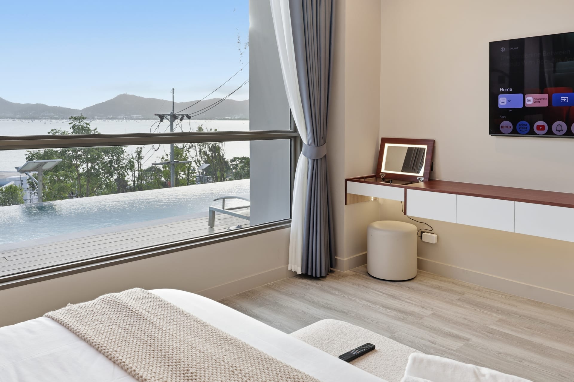 The primary bedroom's desk and console below the TV, with sliding-door access to the balcony and the bay