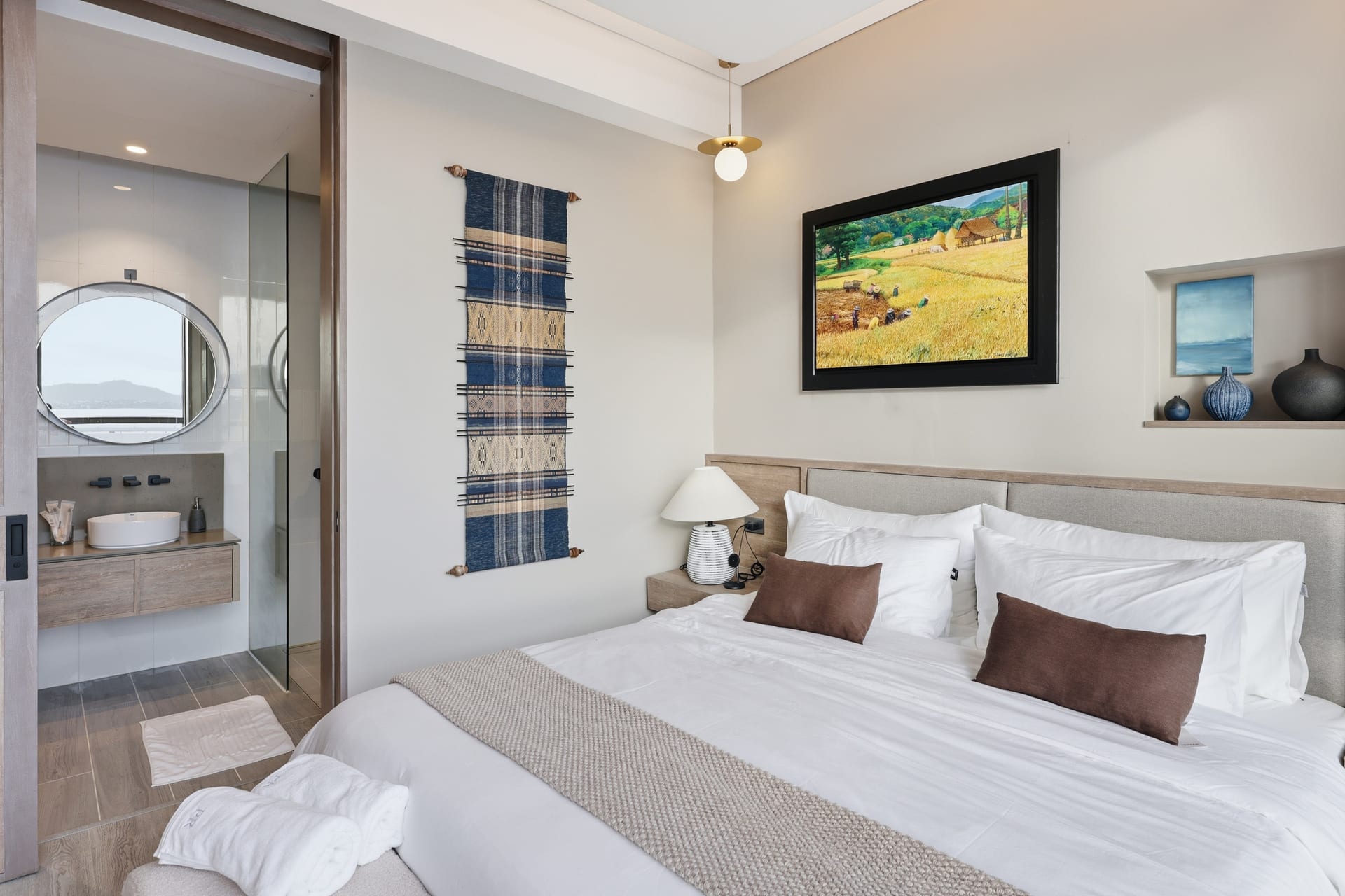 The primary bedroom and its open ensuite bathroom, towels laid out on the bed