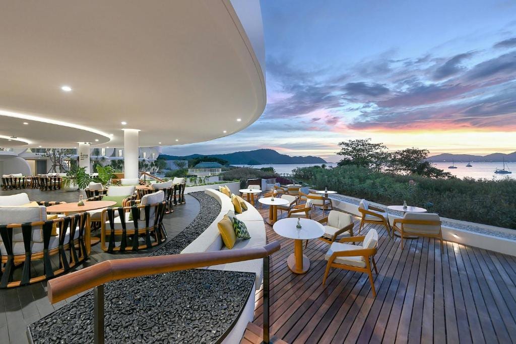 Veranda Resort restaurant terrace at sunset — curved sofa, low tables, the Andaman beyond at dusk