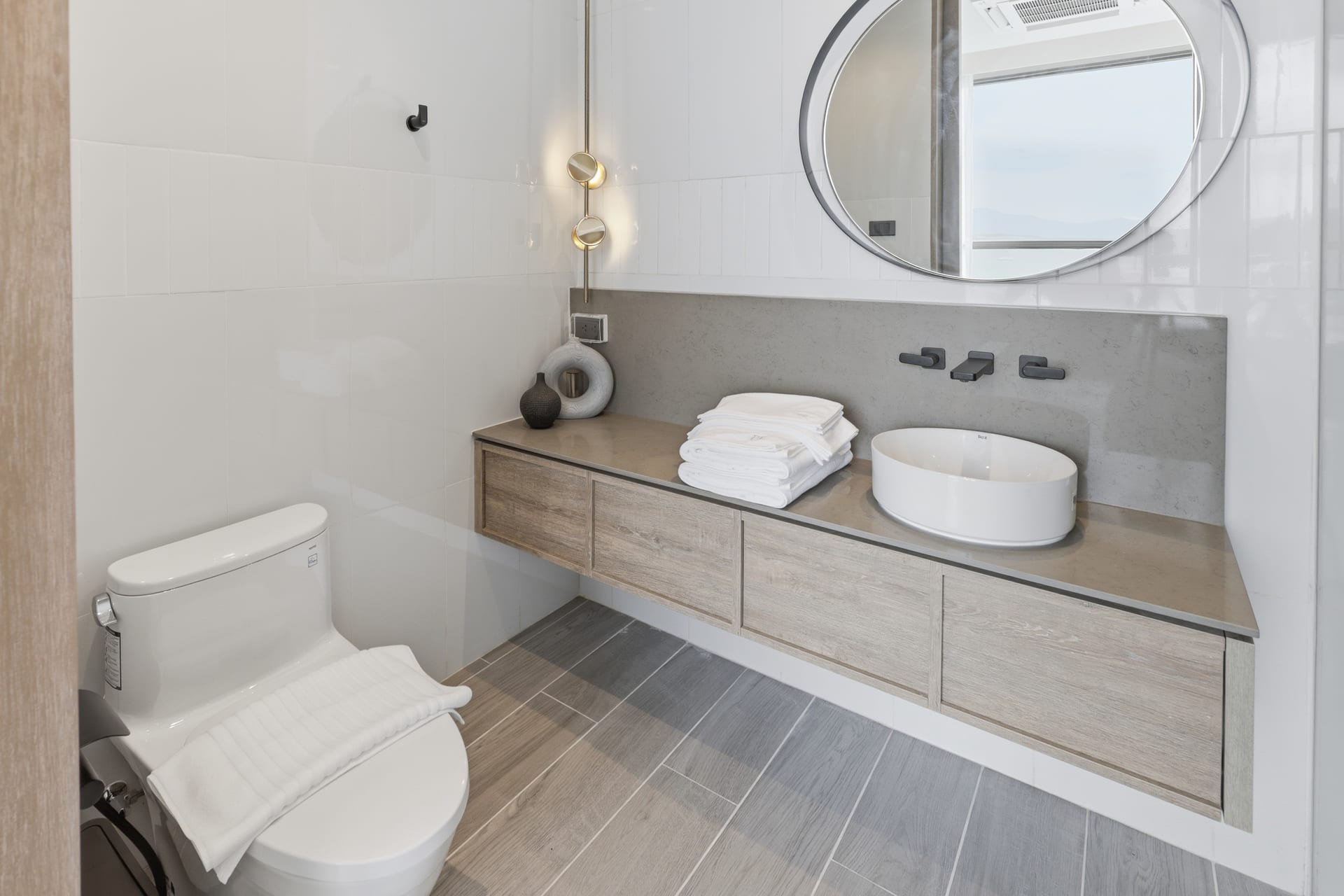 The second bathroom vanity with a round mirror and a bench, walk-in shower alongside