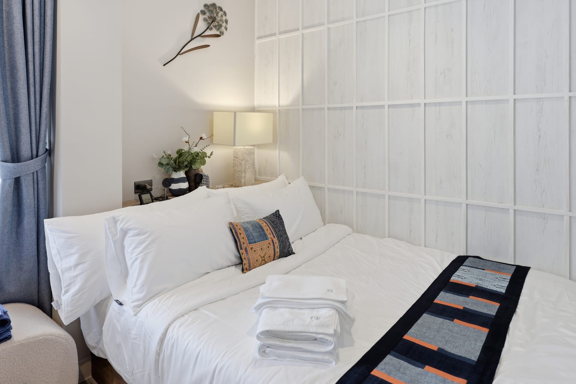 The second bedroom with a queen bed, framed art and a bench with fresh white towels