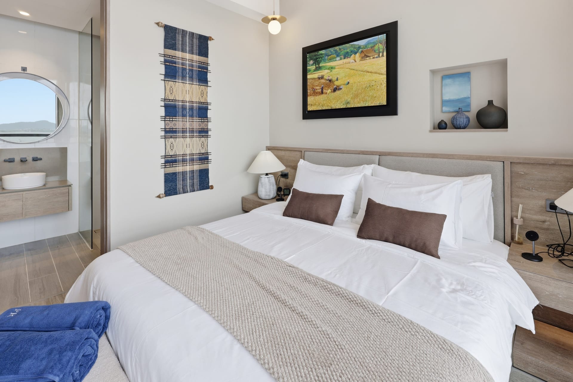 The second bedroom with a queen bed, framed landscape art and a wall-mounted TV